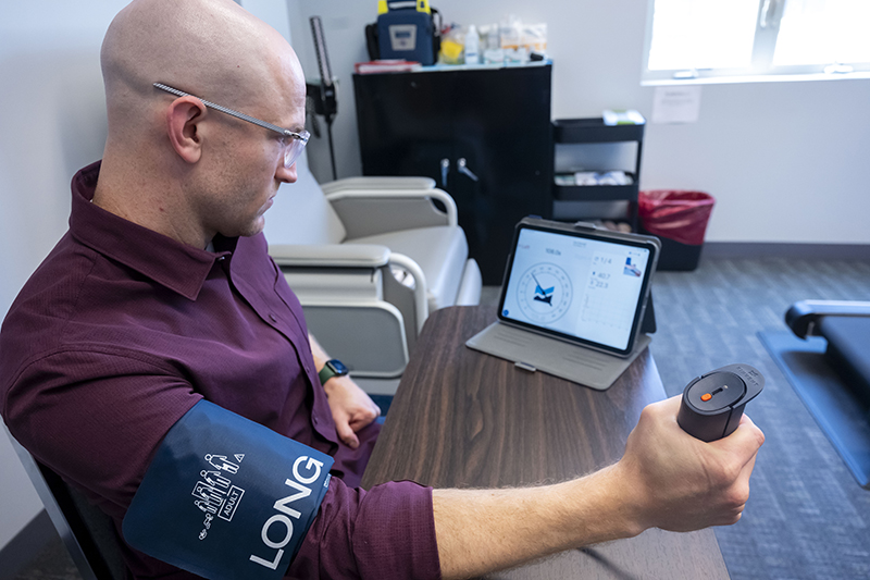 Man holding a handgrip device and wearing a blood pressure cuff