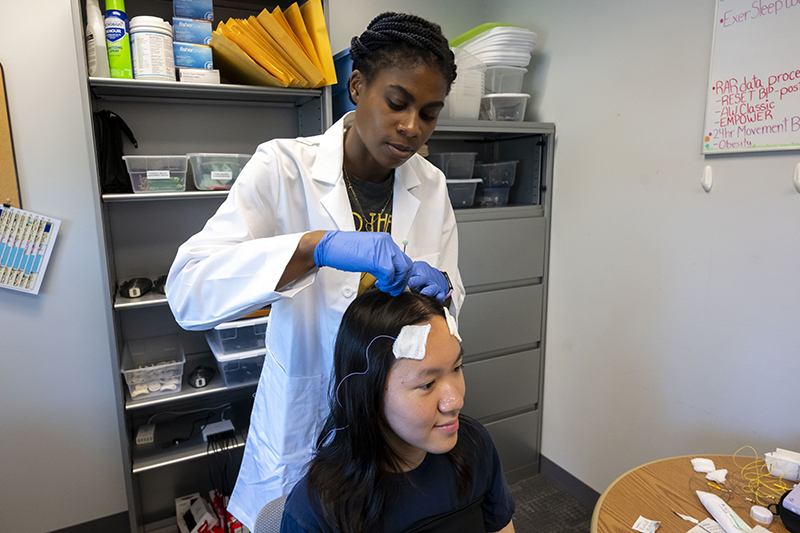 Researcher places sensors on a study participant's head