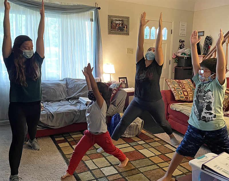 Two adults and two children doing yoga in a living room