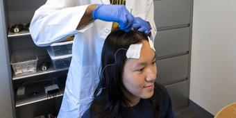 Researcher places sensors on a study participant's head